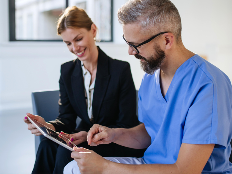 2 people sat on a chair looking at a tablet