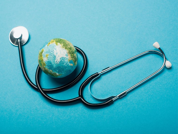 Image of a globe object placed inside a stethoscope, placed on a blue backdrop